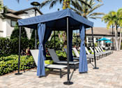 Thumbnail 3 of 40 - a row of lounge chairs under a blue gazebo with umbrellas