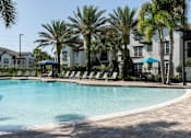 Thumbnail 4 of 40 - a large swimming pool with palm trees in front of an apartment building