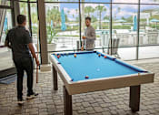 Thumbnail 11 of 30 - two men playing pool in the screened outdoor pavilion