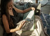 Thumbnail 23 of 42 - woman reading a book on a couch in pixon living room at Lake Nona Pixon, Orlando, Florida