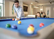 Thumbnail 12 of 30 - man shooting a pool shot and people behind him hanging out