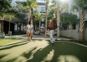 Thumbnail 9 of 42 - Two people enjoying the putting green at LandonHouse Apartments