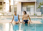 Thumbnail 3 of 42 - Two people sitting on the edge of the pool with their legs in the water in Lake Nona, Orlando, FL 32827