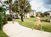Thumbnail 34 of 40 - Little girl running on sidewalk with woman behind her at Lake Nona Water Mark in Orlando, FL