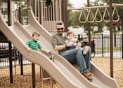 Thumbnail 35 of 40 - Parent playing with his children on the playground at Lake Nona Water Mark
