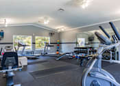 Thumbnail 11 of 33 - A spacious gym with treadmills, elliptical machines, and other exercise equipment.