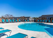 Thumbnail 1 of 33 - A large outdoor swimming pool surrounded by lounge chairs.