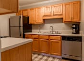 Thumbnail 7 of 33 - A kitchen with wooden cabinets and stainless steel appliances.