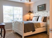 Thumbnail 4 of 33 - A bedroom with a white bed and a window with blinds.