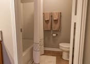 Thumbnail 14 of 33 - A bathroom with a toilet, a towel rack with two towels, and a white pole with a blue pattern.
