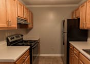 Thumbnail 8 of 33 - A kitchen with wooden cabinets and black appliances.