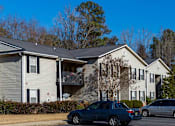 Thumbnail 9 of 33 - A grey and white two story apartment building with a parking lot in front.