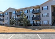 Thumbnail 2 of 33 - Apartment building with a parking lot in front.