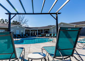 Thumbnail 3 of 33 - A pool area with chairs and a canopy.
