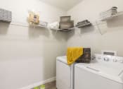 Thumbnail 32 of 44 - Large laundry room with washers, dryers, and built-in shelving at Residences at The Green in Lakewood Ranch, FL