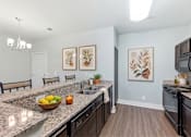 Thumbnail 14 of 15 - A kitchen with granite countertops and a bowl of fruit on it.