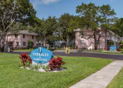 Thumbnail 1 of 32 - Monument signs with tropical plants, mature trees, and well-kept apartment buildings at Terraces at Clearwater Beach, Florida, 33756