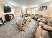 Thumbnail 12 of 19 - A living room with a grey carpet and a large selection of recliners.at The Lodge at Johns Road Apartments, Huntsville, AL, 35806