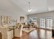 Thumbnail 6 of 12 - A well-lit living room with a glass table and chairs.