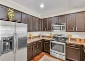 Thumbnail 4 of 12 - A kitchen with brown cabinets and stainless steel appliances.