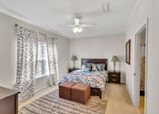 Thumbnail 8 of 12 - A bedroom with a patterned bedspread and a ceiling fan.