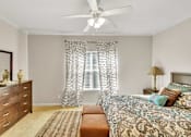 Thumbnail 9 of 12 - A bedroom with a bed, dresser, and window with curtains.