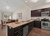 Thumbnail 3 of 28 - A kitchen with dark brown cabinets and a granite countertop.