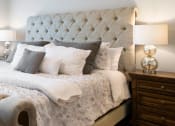 Thumbnail 2 of 8 - a bed with a tufted headboard and fluffy pillows in a bedroom
