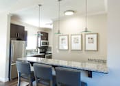 Thumbnail 30 of 33 - A kitchen with a granite countertop and a refrigerator.