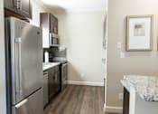 Thumbnail 31 of 33 - A kitchen with a refrigerator, microwave, and cabinets.