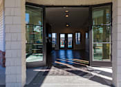 Thumbnail 22 of 33 - A white building with a glass door entrance.