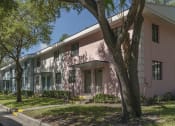 Thumbnail 4 of 32 - Mature trees and neat sidewalks in front of pastel apartment homes at Terraces at Clearwater Beach, Clearwater