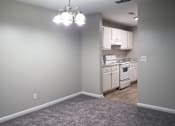 Thumbnail 5 of 8 - Apartment living room with a chandelier and a kitchen in the background at The Bluffs in Jasper, Alabama