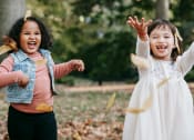 Thumbnail 8 of 8 - two young girls playing outside and tossing autumn leaves in the air