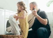 Thumbnail 4 of 8 - a father and daughter pulling fresh laundry out of an in-home dryer