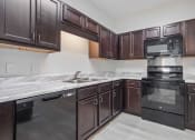 Thumbnail 3 of 57 - a kitchen with dark wood cabinets and black appliances