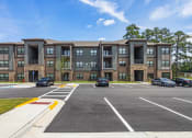 Thumbnail 44 of 57 - a large apartment building with cars parked in a parking lot