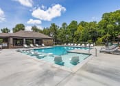 Thumbnail 16 of 57 - the resort style pool with lounge chairs and a building in the background