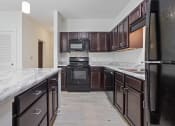 Thumbnail 35 of 57 - a kitchen with dark wood cabinets and marble counter tops