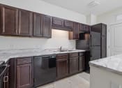 Thumbnail 33 of 57 - a kitchen with dark wood cabinets and marble counter tops