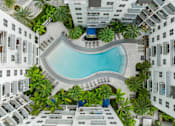Thumbnail 1 of 40 - A swimming pool surrounded by palm trees and buildings.