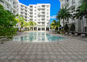 Thumbnail 37 of 40 - A swimming pool surrounded by a tiled floor and palm trees.