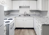 Thumbnail 5 of 8 - a kitchen with white cabinets and white appliances and wood-style flooring at Woodland Villas Apartments, Jasper
