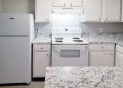 Thumbnail 6 of 8 - a kitchen with white appliances, white cabinets, and granite-inspired countertops at Woodland Villas Apartments, Jasper Alabama
