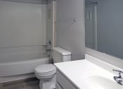 Thumbnail 8 of 8 - bathroom with large sink vanity and mirror, wood-style flooring and toilet, shower/tub at Woodland Villas Apartments, Alabama