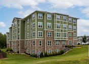 Thumbnail 182 of 197 - A large apartment building with a green and brown exterior at Foxwood Apartments, Raleigh-Durham, NC, 27616