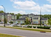 Thumbnail 181 of 197 - Apartment complex with green and brown buildings and cars parked in front at Foxwood Apartments, Raleigh-Durham, North Carolina