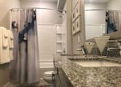 Thumbnail 94 of 197 - A bathroom with a marble counter top and a shower curtain. at Foxwood Apartments, Raleigh-Durham, NC