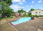 Thumbnail 1 of 31 - A swimming pool surrounded by a concrete patio and a red umbrella.
