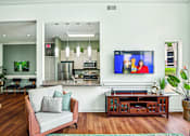 Thumbnail 20 of 31 - A living room with a grey couch and a television on the wall.
